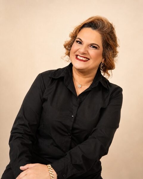 Mirian Sahd Jobbins, psicóloga, sorrindo de camisa preta em retrato profissional