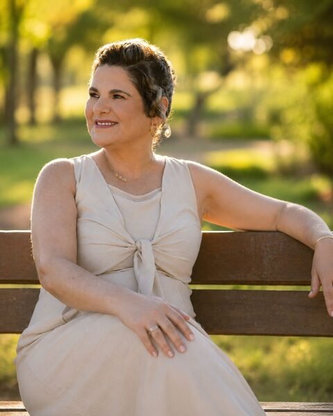 Mirian Sahd Jobbins sentada em um banco em ambiente natural, em retrato acolhedor ao entardecer